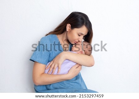 Beautiful young mother with a newborn daughter in a diaper on a white background. Motherhood. Tenderness. Space for text. High quality photo Royalty-Free Stock Photo #2153297459