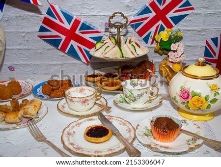 Queen Elizabeth II Platinum Jubilee cream tea street party food red white and blue flags with celebration Union jack food twhite vintage table cloth with Union jack flags king charles  coronation Royalty-Free Stock Photo #2153306047