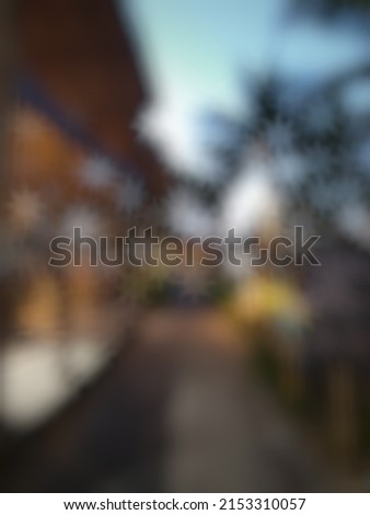 Defocused or blurred abstract background of a straight jogging track flanked by a restaurant on the left and a small garden on the right side