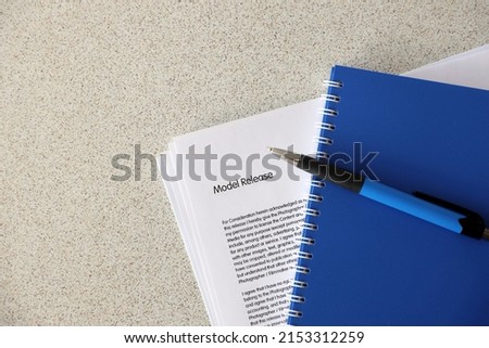 Model release blank form with blue notepad and blue pen lies on photographers table. Model release signing photo concept