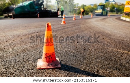 Traffic cones on road. A large layer of fresh hot asphalt. Road construction.