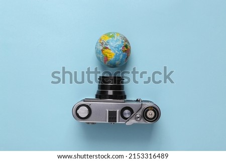 Travel concept. Retro camera with globe on blue pastel background. Top view