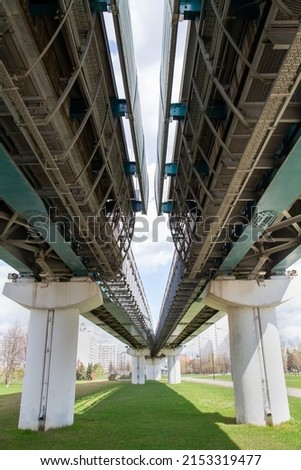 View of the supports and metal spans of the light metro on a clear sunny day against the blue sky. Transport railway technology.