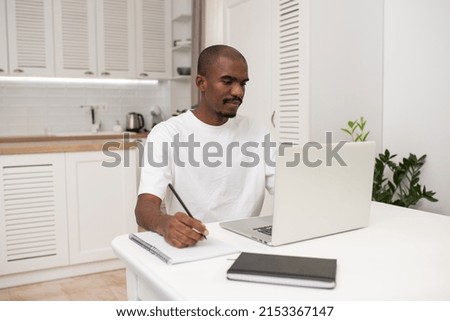 Handsome black freelancer guy working on a laptop at home, Sitting at the desk with laptop, Looking at device screen, Enjoying freelance Job. Remote work.