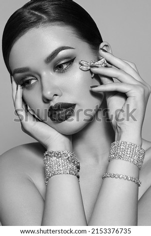 A beautiful, luxurious young girl with bright makeup sits in shining jewelry. Bracelets and brooch. Luxurious jewelry, diamonds.