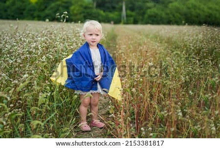 flag of Ukraine in hands of smiling little girl. happy child carries yellow-blue flag. day of Ukraine's insability