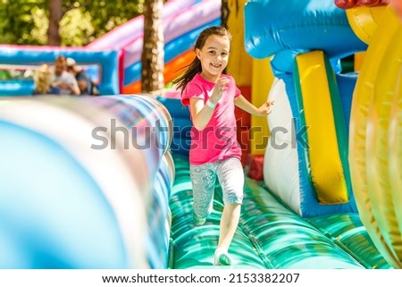 Happy little girl having lots of fun on a jumping castle during sliding. Royalty-Free Stock Photo #2153382207