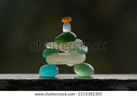 closeup view of sea glass pebbles of different colours balances on a wood plank