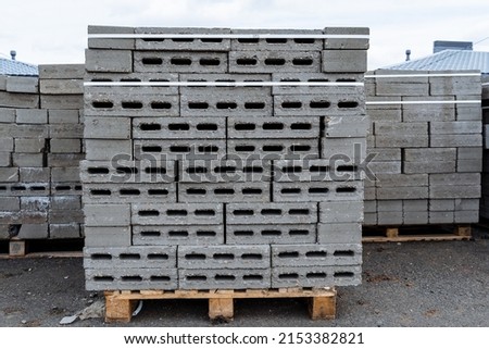 The packaging of concrete blocks lies on a pallet, the packaging of bricks is stacked in a heap, holes in the bricks, building material, a construction site, a storage warehouse. High quality photo