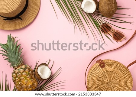 Summer holidays concept. Top view photo of round rattan bag hat pineapple cracked coconuts sunglasses and palm leaves on isolated pastel pink background with empty space in the middle