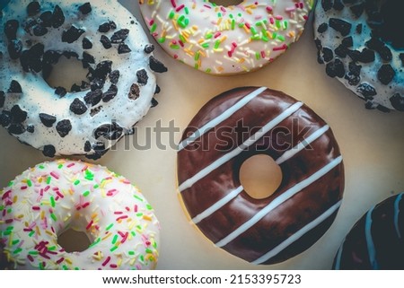Flat lay image of donut with chocolate glaze with stripes amids other different donuts