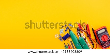 Arrangement of tools for repairing automotive electrical wiring on a yellow background. selective focus