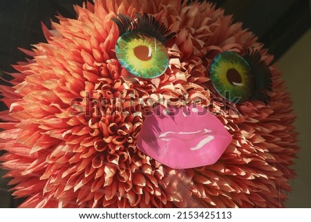 Handmade female face with big green eyes, long black eyelashes and lips painted with pink lipstick. Ironic portrayal of artsy female unnatural beauty. Closeup photography, modern abstract  portrait Royalty-Free Stock Photo #2153425113