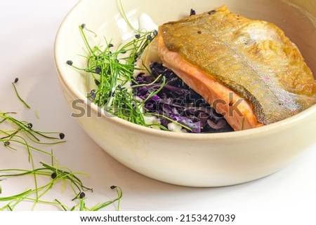 Char fish filet roasted on the skin with red cabbage kimchi, cream sauce and sprouts served in a bowl, selected focus, narrow depth of field