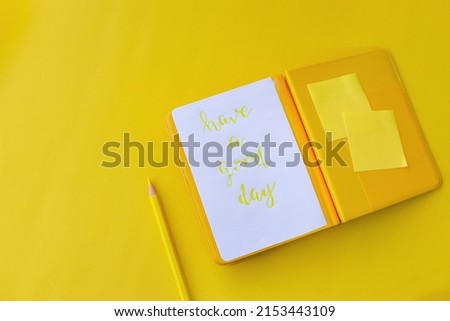 Notes, pencil and post-it paper on a yellow background with the phrase Have a good day. Copy space and mock up for lifestyle, business and education. Creative monochrome yellow mood. 