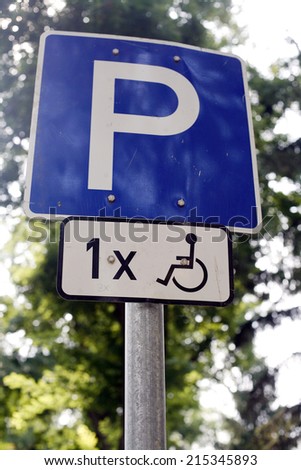 	A blue road sign with a capital P. 	Parking place for wheelchairs in the city. Road sign with nature background