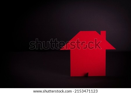 red paper cutout in plain house shape on black background with copyspace, in concept of business, banking and outstanding.