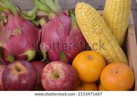 Red apples, Yuzu oranges, corn, dragon fruit arranged in wooden boxes. Red fruits and vegetables contain lycopene. Yellow and orange fruits contain carotenoids, vitamin C.