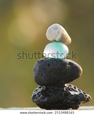 closeup view of sea glass pebbles and a tiny sea shell balances on a lava stone