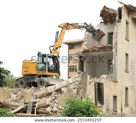 Wheeled excavator demolishing an old building for an urban redevelopment. Royalty-Free Stock Photo #2153492259
