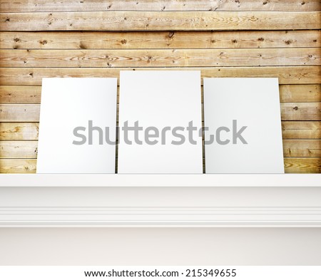 White posters on a shelf and wooden wall