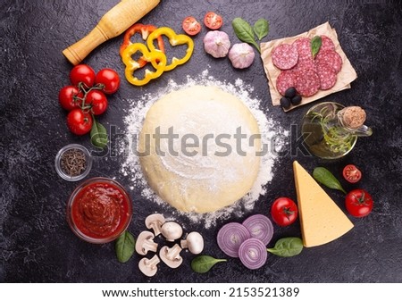 Food ingredients and spices for cooking mushroom, tomato, cheese, onion, oil, pepper, salt, basil, olive and delicious Italian pizza on a black concrete background. Copyspace. View from above. Banner Royalty-Free Stock Photo #2153521389