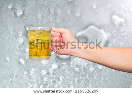Hand holding a glass of ice and cold beer on a cold flake background.