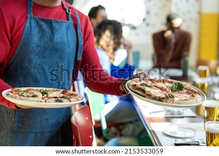 Waiter serving delicious pizza in cozy pizzeria restaurant - Italian pizza in italian restaurant - Hands of waiter holding two pizzas Margherita - Original recipe of italian tasty pizza margherita Royalty-Free Stock Photo #2153533059