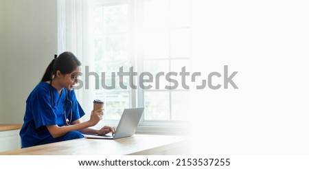 A young Asian nurse confidently works with her laptop in the clinic.
health care concept happy doctor or nurse in hospital banner image