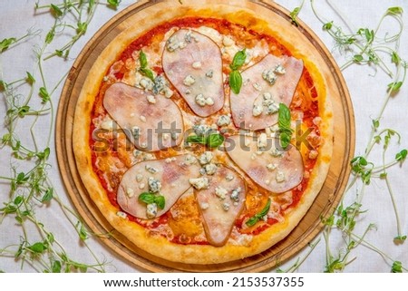 Traditional pizza with pear, nuts and blue cheese on a wooden background