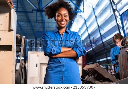 Engineer african woman wearing safety helmet working and checking machine  automotive part warehouse factory.Happy female  worker looking at the camera.