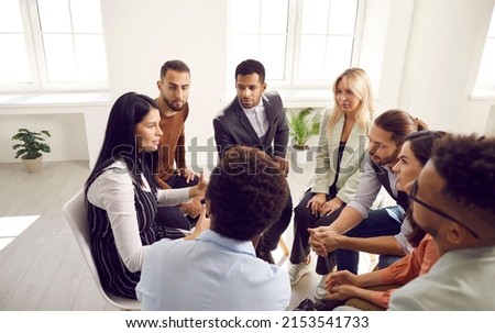 Young inexperienced business team meeting with coach for professional advice and training. Group of people listening to speaker sharing opinion and explaining why coordinated teamwork is so important Royalty-Free Stock Photo #2153541733