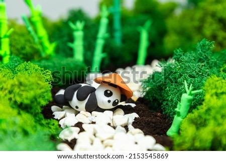 Funny homemade plasticine panda in a stylized jungle. Concept for world animal day, panda day, earth day. Environmental protection.