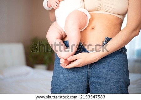 Mom's abdomen after cesarean section. Scar seam. A young mother holds the baby in her arms. Real motherhood. Lifestyle. High quality photo Royalty-Free Stock Photo #2153547583