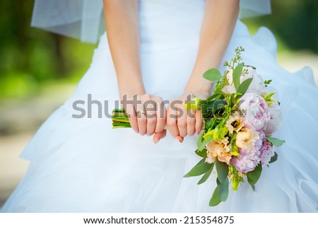 Beautiful wedding bouquet in hands of the bride. Wedding rings.