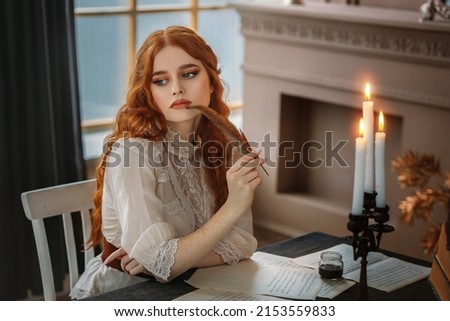 Portrait red-haired vintage woman writer holding bird feather in hands. Medieval girl sit at table writes book, letters on sheets paper with ink pen. Photo old retro style. White blouse, classic room. Royalty-Free Stock Photo #2153559833