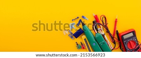 Arrangement of tools for repairing automotive electrical wiring on a yellow background. selective focus