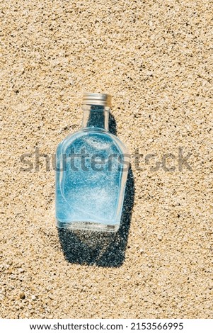 Blue water in a glass bottle on sands at a beach, Memory of summer vacation, Tropical background