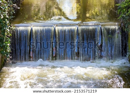An artificial waterfall on a stream Royalty-Free Stock Photo #2153571219