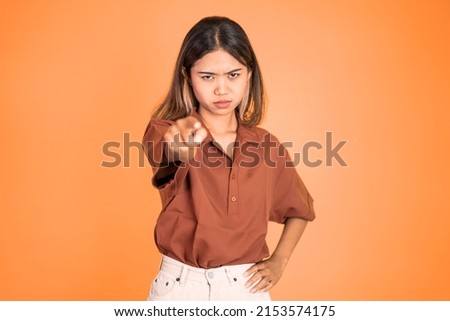 unhappy and angry asian woman with finger pointing to camera
