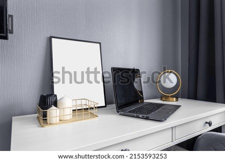 Desk with blank pictures, a laptop, candles, a picture and a table lamp in the form of a ball