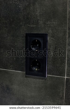 New black rosette on a ceramic tile of black color. Electrical outlet. Bathroom
