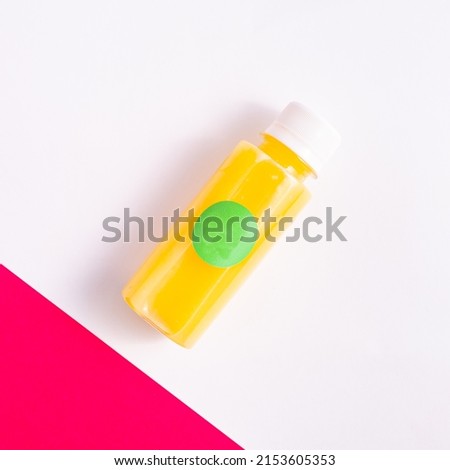 Lemon juice bottle. Yellow plastic bottle isolated on purple white background