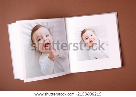 Baby's photo book on brown background . Children's emotional portrait.Cute toddler boy