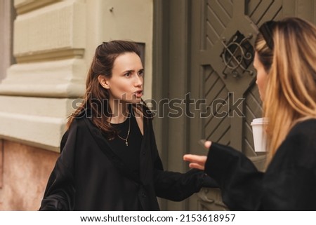 Quarrel two friends. Two women screaming at each other. Two young women argue near door outdoor on the street. Family problem. Angry female show emotion. Depression people. Stress family photo. Royalty-Free Stock Photo #2153618957