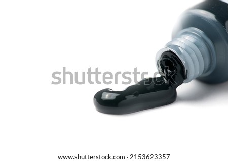 Close-up of an open tube of black acrylic artist paint oozing out on a white background.