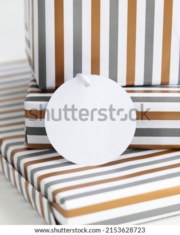 Presents with blank round gift tag close up. Gift boxes wrapped in Striped geometric paper. Christmas, New Year, Birthday, Anniversary label mockup