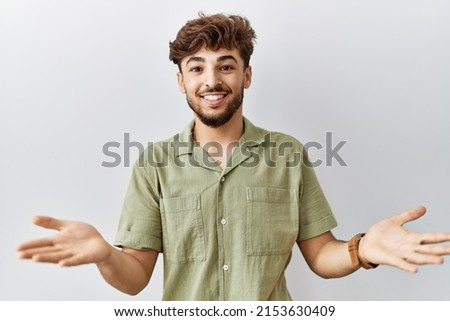 Young arab doctor man standing over isolated background smiling cheerful offering hands giving assistance and acceptance. 