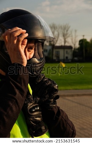 A novice biker is being trained at an atoschool. Close-up of a motorcyclist in a helmet and training vest. Biker emotions. Royalty-Free Stock Photo #2153631545