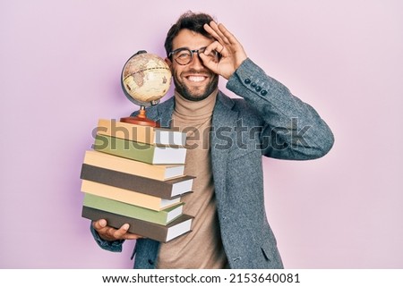 Handsome man with beard geography teacher smiling happy doing ok sign with hand on eye looking through fingers  Royalty-Free Stock Photo #2153640081